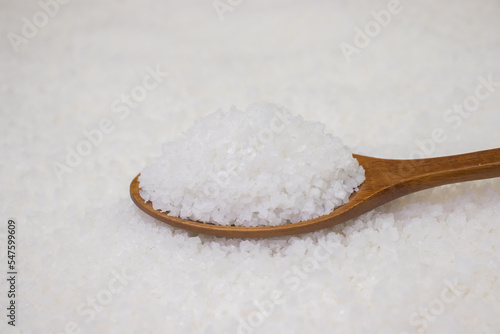 Salt in wooden spoon on salt background. photo