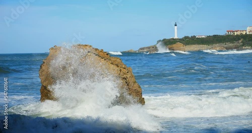 Swell breaking on the beach of Biarritz in the Basque Country with the lighthouse on the horizon (in slow motion)