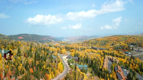 Drone shot of the highway, buildings and tree-covered fields in Brian Head, Utah under a blue sky