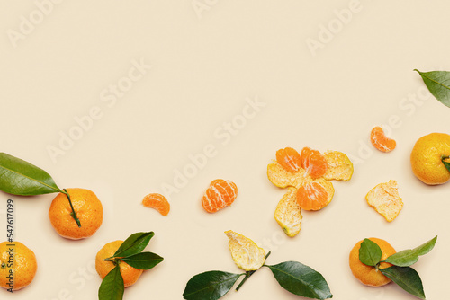 Fototapeta Naklejka Na Ścianę i Meble -  Orange yellow juicy tangerines with green leaves, whole and peeled on neutral beige background with copy space. Citrus fruits mandarins, healthy fruits food concept, creative styled photo