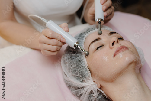  A young European woman, a brunette, is undergoing a microcurrent galvanic face lift with the help of electrodes. The concept of preventing the problem of acne and oily skin. photo