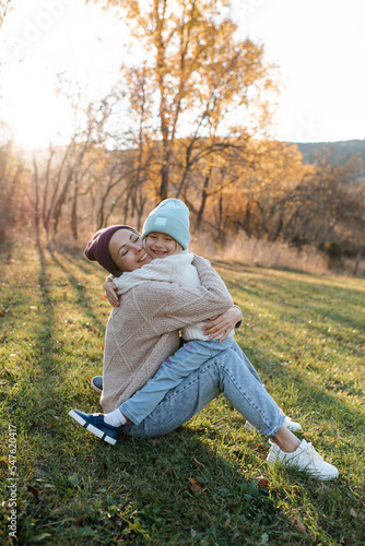 Smiling happy mother holding little baby girl wear casual clothes in autumn park outdoor. Family content. Motherhood.