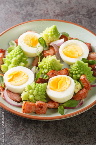 Salad Romanesco cauliflower buds with boiled eggs, red onion and bacon closeup on the plate on the table. Vertical