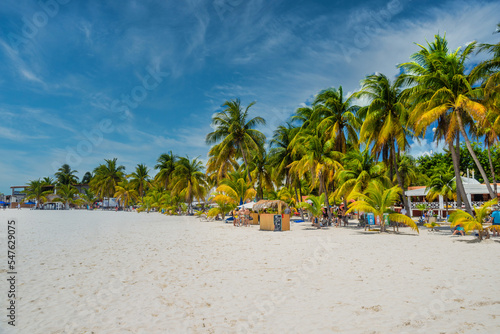 Fototapeta Naklejka Na Ścianę i Meble -  ISLA MUJERES ISLAND, MEXICO - APR 2022: Cocos beach bar on a beach with white sand and palms on a sunny day, Isla Mujeres island, Caribbean Sea, Cancun, Yucatan, Mexico
