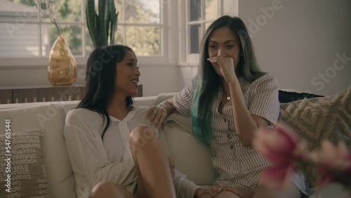 women talking and remembering a funny event while sitting on sofa in living room