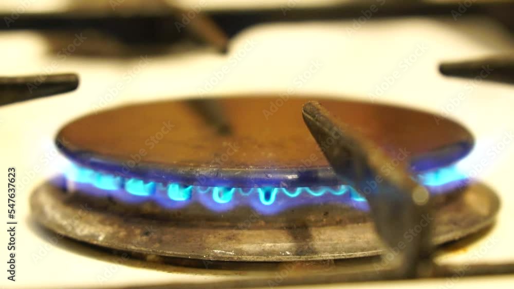 Natural gas burning on white enameled domestic stove at kitchen. Close up of natural gas flames in gas stove on the domestic kitchen. Concept of problems with gas, rising prices. Slow motion. Natural gas burning on white enameled domestic stove at kitchen. Close up of natural gas flames in gas stove on the domestic kitchen. Concept of problems with gas, rising prices. Slow motion.