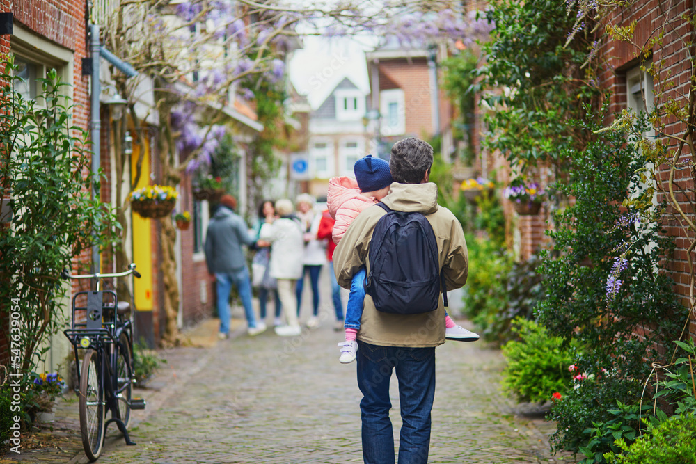 Father with daughter walking in beautiful street decorated with flowers in the town of Alkmaar, Netherlands