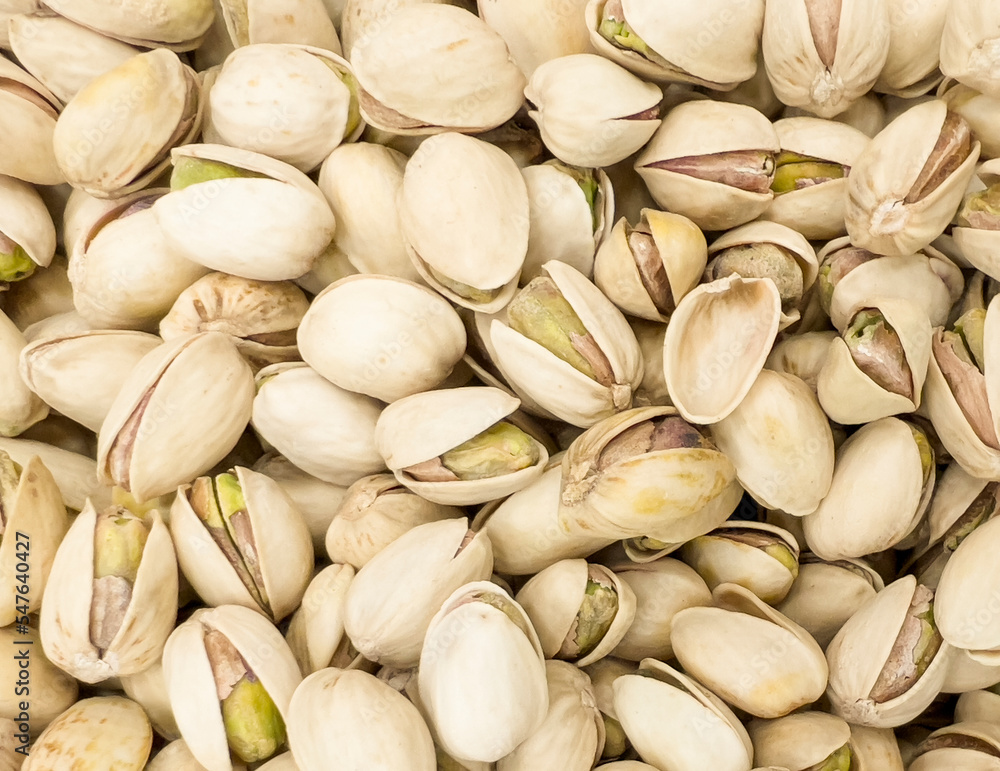 Background of organic pistachios. Natural pure pistachios nuts texture background. Scattered pistachios grains pattern