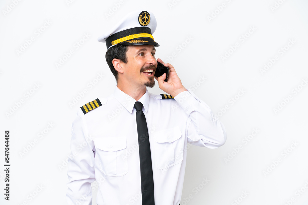 Airplane caucasian pilot isolated on white background keeping a conversation with the mobile phone Airplane caucasian pilot isolated on white background keeping a conversation with the mobile phone