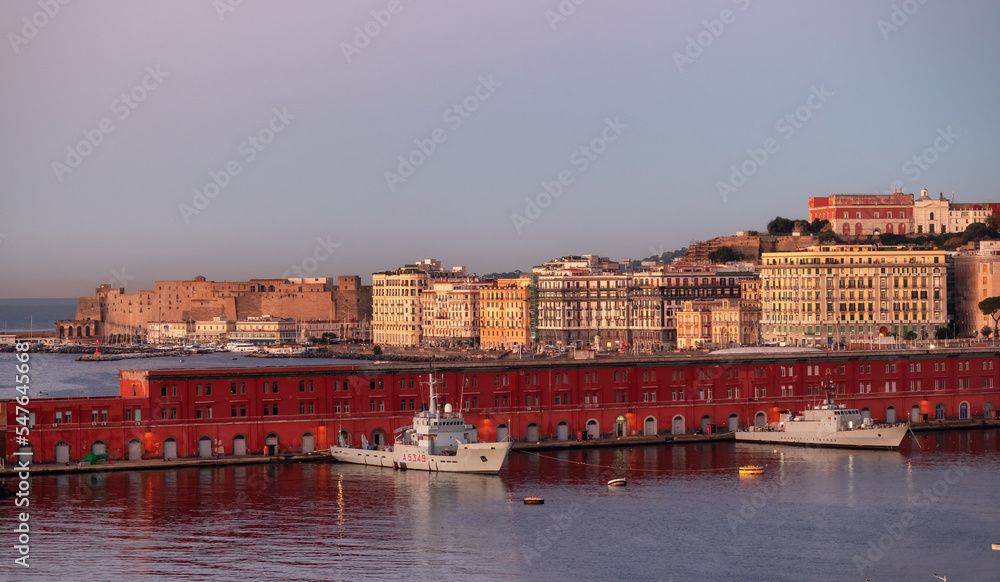 Navy Warship at a port with Historic Downtown City on Mediterranean Coast of Naples, Italy. Sunrise Sky.