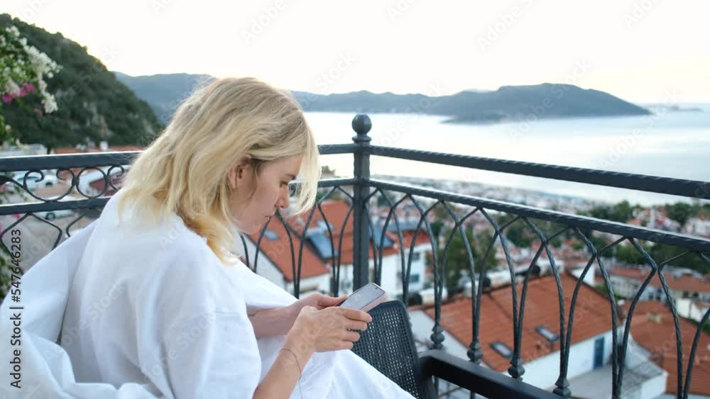 a girl with a phone sits on a balcony against the backdrop of the city of Kas Turkey a girl with a phone sits on a balcony against the backdrop of the city of Kas Turkey