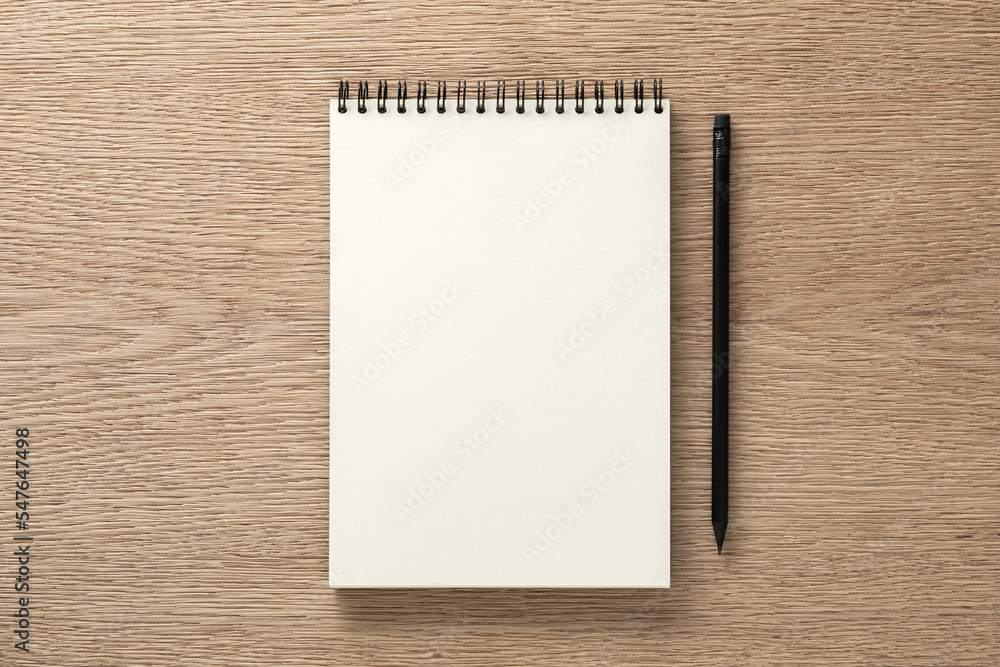 Notebook and black pencil on oak desk. Flat lay. Top view Notebook and black pencil on oak desk. Flat lay. Top view