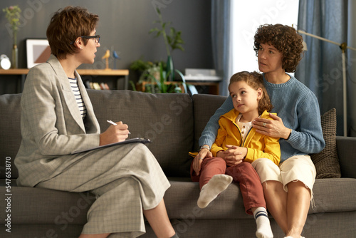 Fotografie Social worker making notes while talking to adoptive parent and child during the