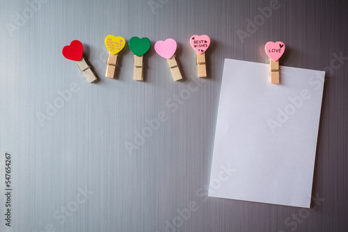 Abstract of wooden heart clip with Blank paper and stick paper on refrigerator door. paper note copy space for add text. valentine picture message background