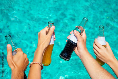Photography best friends drinking lemonade while refreshing in the swimmingpool hands close