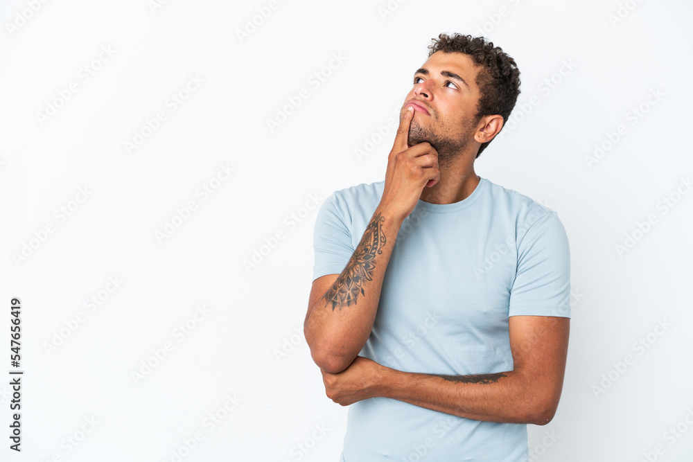 Young handsome Brazilian man isolated on white background having doubts while looking up Young handsome Brazilian man isolated on white background having doubts while looking up