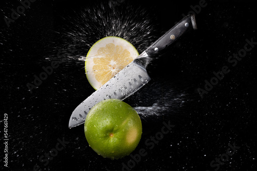 Fresh ripe oroblanco cutting with a knife and flying in motion on the black background with red splashes photo