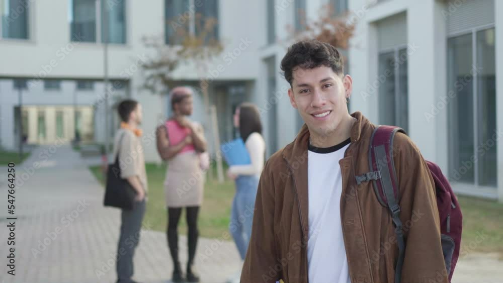 student boy looking at camera while his friends are behind talking, in university campus. student boy looking at camera while his friends are behind talking, in university campus.