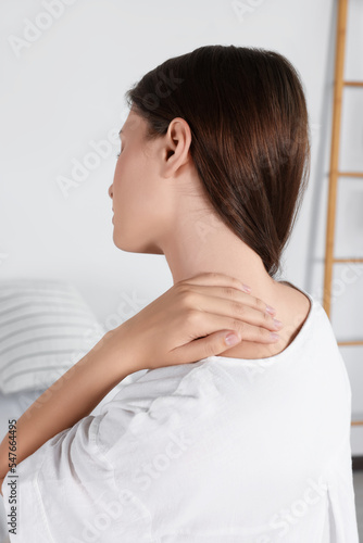 Woman suffering from neck pain in room