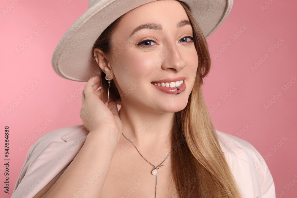 Young woman with lip and ear piercings on pink background Young woman with lip and ear piercings on pink background