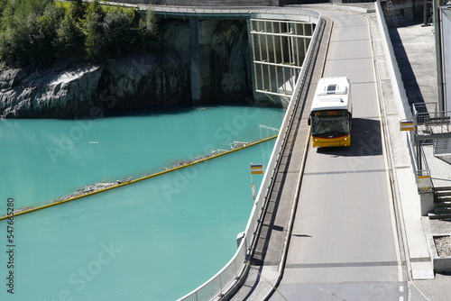 View on the bridge with yellow autobus of hydroelectric power plant on reservoir Mapraggsee. The power plant belongs to company called Kraftwerke Sarganserland AG.  photo