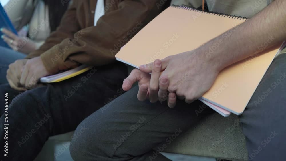 close up of the hands of some students sitting in a university campus. close up of the hands of some students sitting in a university campus.