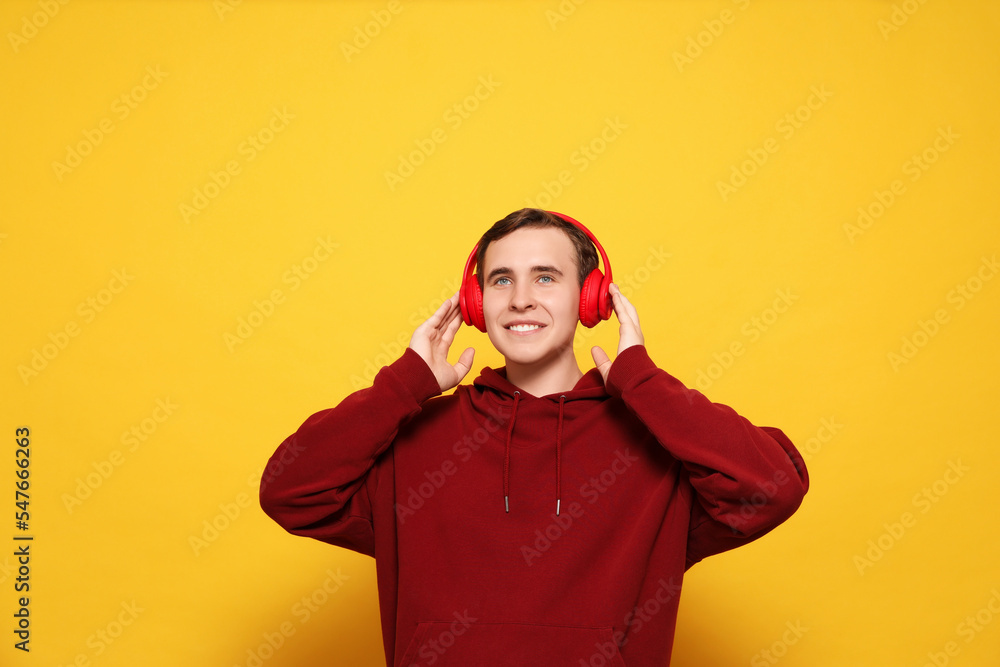 Fototapeta premium Handsome young man with headphones on yellow background