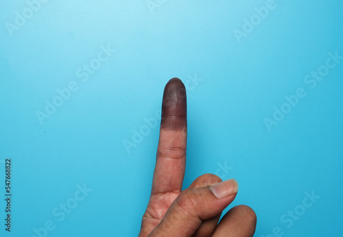 A picture of finger with indelible ink on blue background. Confirmation voting during Malaysia General Elections.