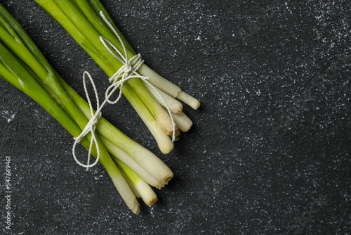 Bunch of fresh green onion on black table  flat lay. Space for text