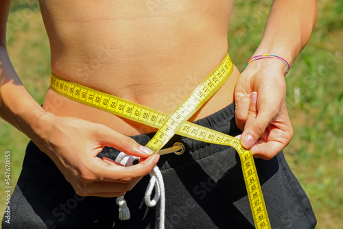 Obraz na plátně young girl measuring her waistline with a yellow flexible tape measure