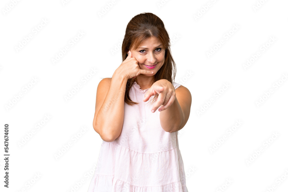 Middle age woman over isolated background making phone gesture and pointing front Middle age woman over isolated background making phone gesture and pointing front