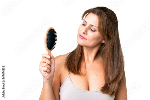 Middle age woman over isolated background with hair comb and looking it