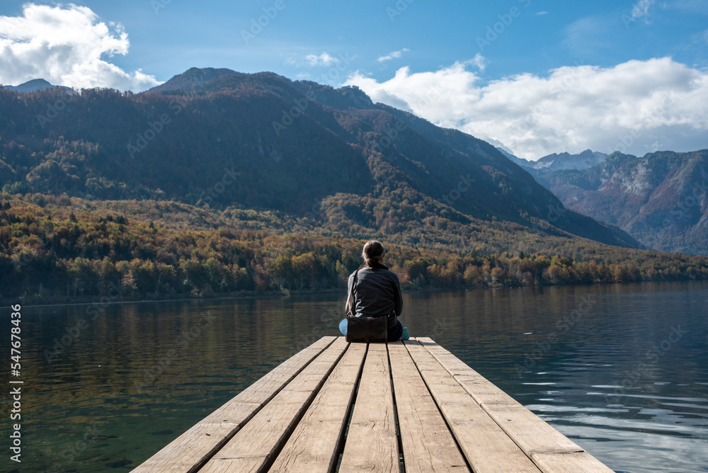 Sitting on a small jetty and enjoying the view on the landscape of lake Bohinj in the Triglav National Park, The Julian Alps of Slovenia