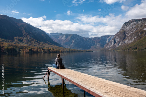 Sitting on a small jetty and enjoying the view on the landscape of lake Bohinj in the Triglav National Park, The Julian Alps of Slovenia © imagoDens