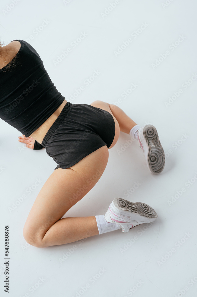 Close photo of a woman with a sexy booty in short shorts and sneakers  dancing twerk on a white background. Stock Photo | Adobe Stock