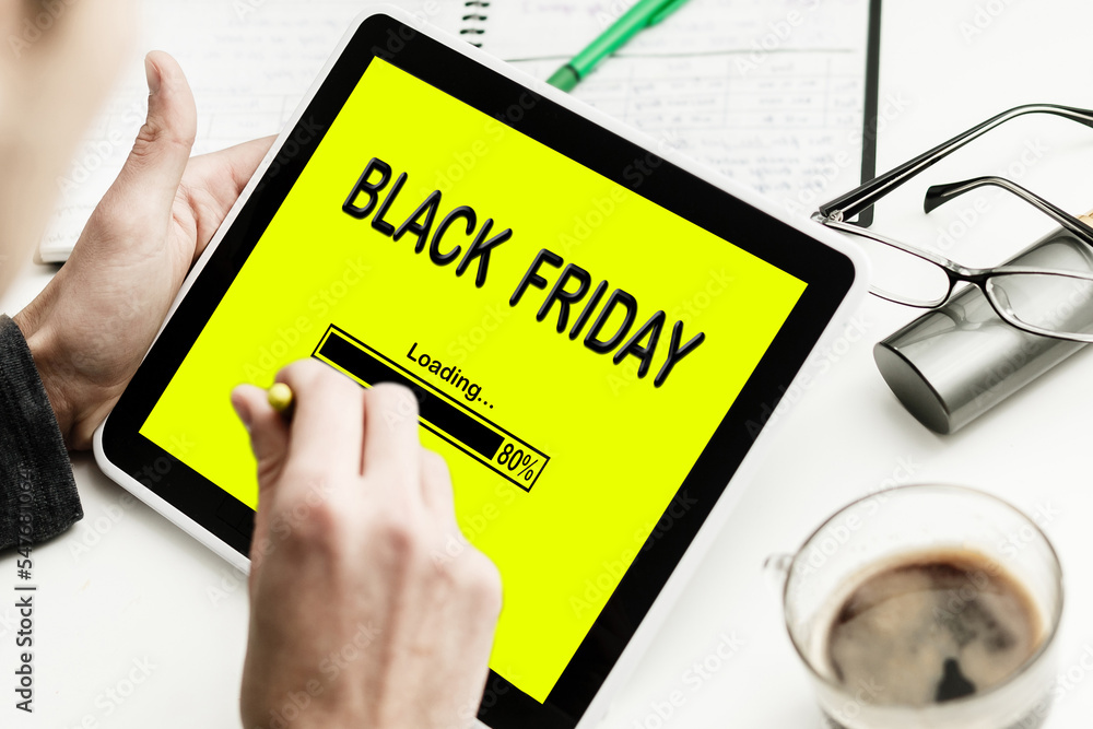 Laptop and small cart on white marble table. Black Friday Sale online Laptop and small cart on white marble table. Black Friday Sale online