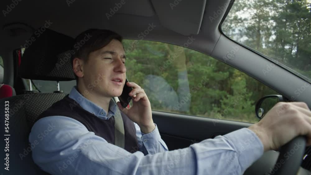 The man behind the wheel is talking on the phone, losing his balance. Office worker driving a car on a sunny day and using the phone, traffic violation. High quality 4k footage The man behind the wheel is talking on the phone, losing his balance. Office worker driving a car on a sunny day and using the phone, traffic violation. High quality 4k footage