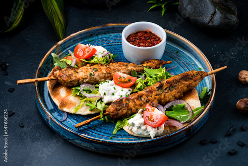 Fototapeta Naklejka Na Ścianę i Meble -  Fresh kebab, barbecued chicken on a stick with tomatoes, lettuce, onion, arugula, sour cream, tortilla and red sauce.