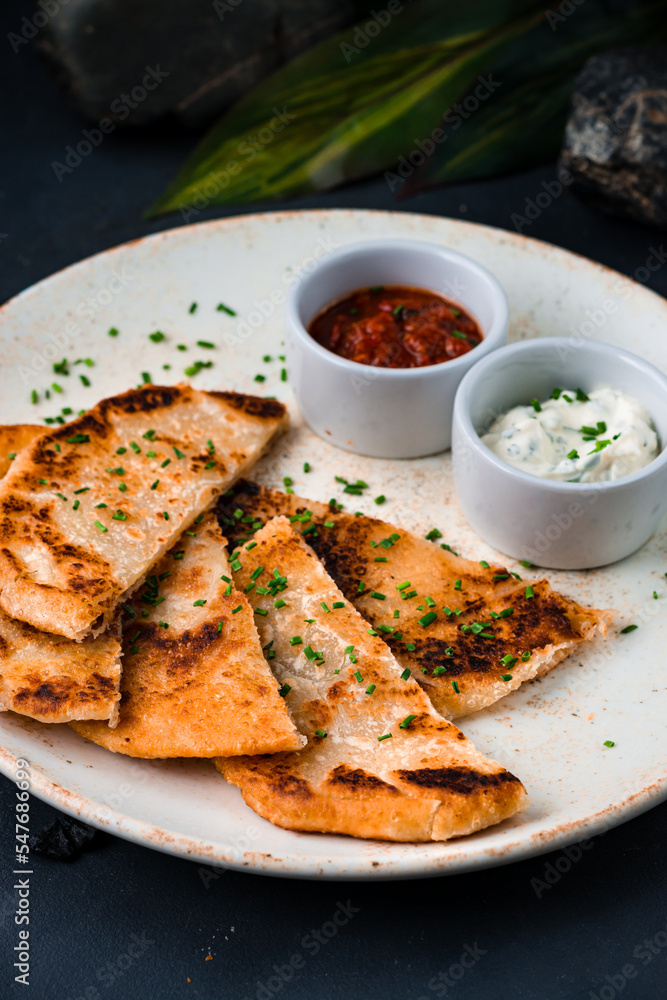 Sliced fried tortillas with sour cream sauce and tomato salsa.