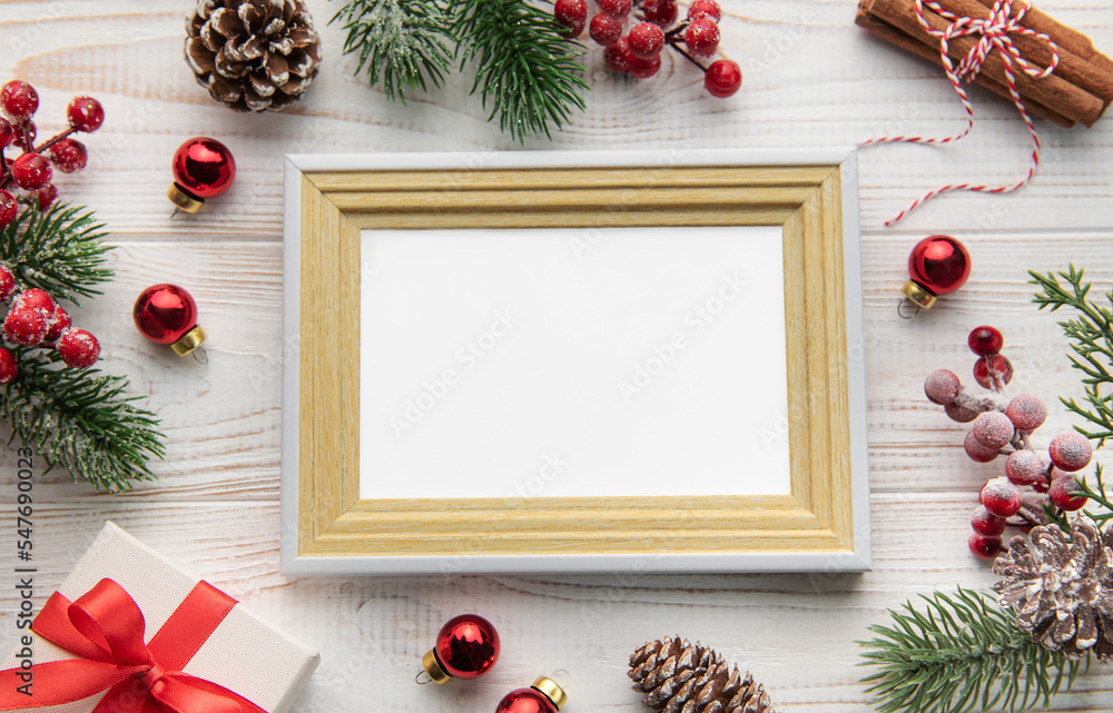 Fototapeta premium Photo frame, decorations, fir tree branches on white wooden background