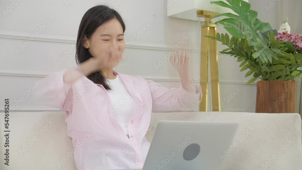 Happiness young asian woman sitting on sofa and working on laptop computer finish while successful and excitement at home, freelance using notebook and achievement, business and lifestyles concept.