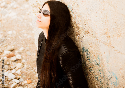 Woman with classic sunglasses on a cloudy day, dressed in a black leather jacket