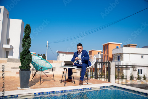 Adult businessman using laptop and phone