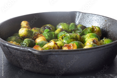 Sprouts fried  in a cast iron frying pan wiyth olive oil  on a slate board. Isolated on a white background