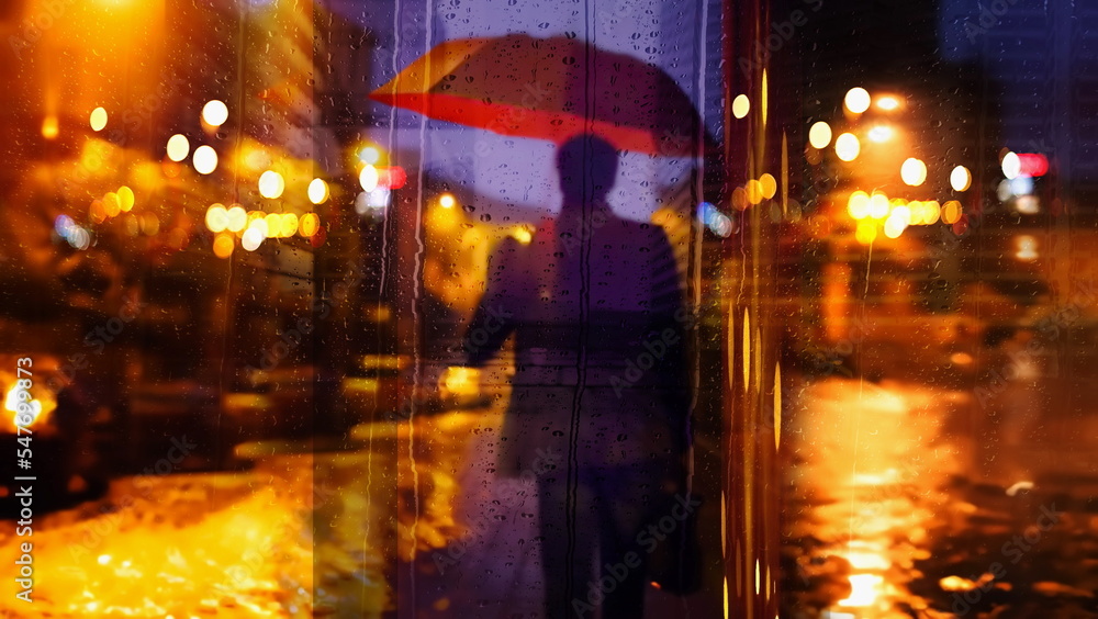  man with red umbrella walk on evening city street blurred street lamp reflection rain fall drops