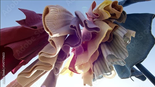 Low angle view of colourful clothes hanging on rail outdoors against blue sky.