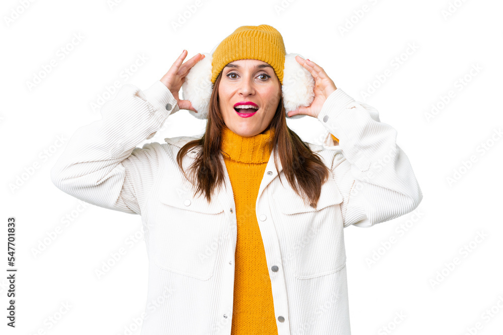 Middle age woman wearing winter muffs over isolated chroma key background with surprise expression Middle age woman wearing winter muffs over isolated chroma key background with surprise expression