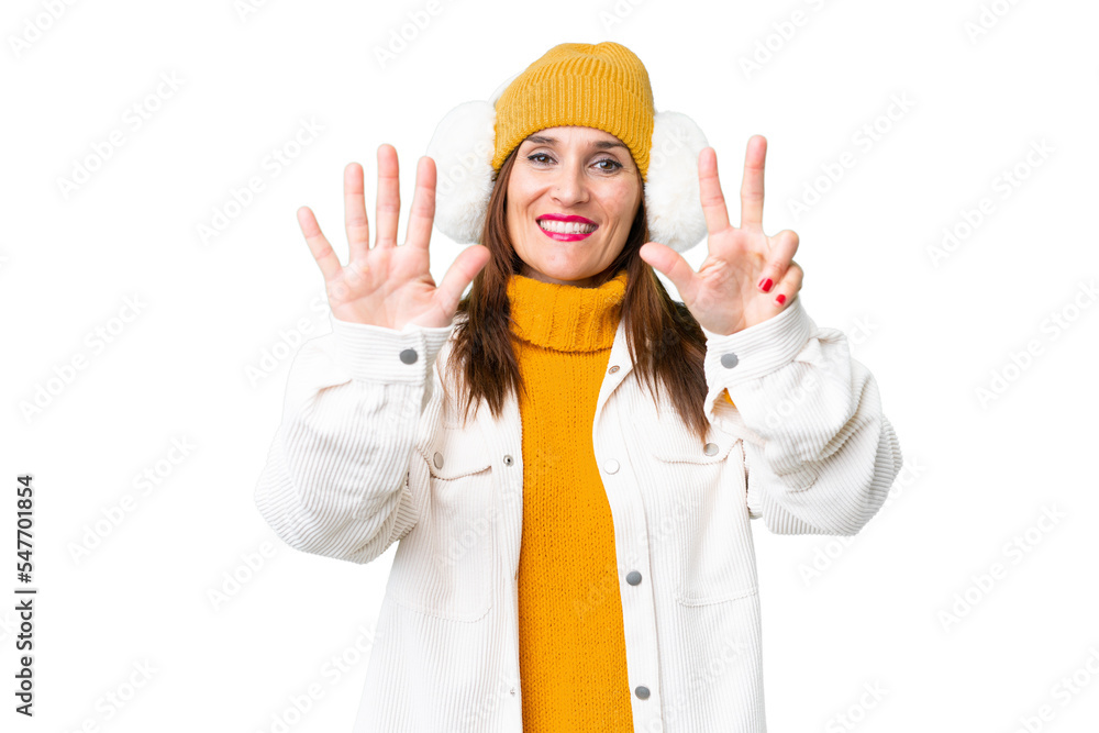 Middle age woman wearing winter muffs over isolated chroma key background counting eight with fingers Middle age woman wearing winter muffs over isolated chroma key background counting eight with fingers