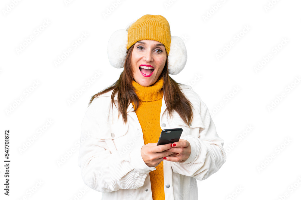 Middle age woman wearing winter muffs over isolated chroma key background surprised and sending a message Middle age woman wearing winter muffs over isolated chroma key background surprised and sending a message