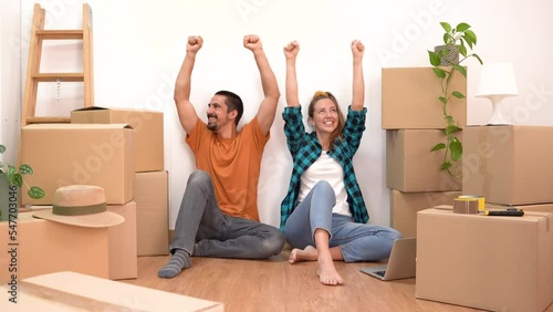 Couple with moving boxes happy celebrating in their new home household move. Attractive young friends in love smiling together. High quality 4k footage photo